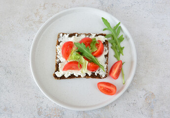 Healthy Open-Faced Sandwich with rye bread and Cream Cheese, Tomato slices and Arugula