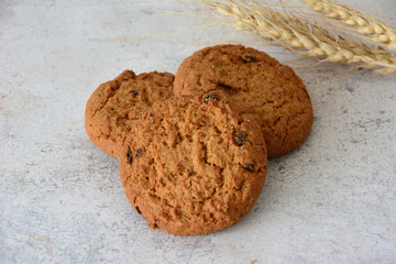 Delicious Oatmeal Raisin Cookies on a Textured Surface with ears of wheat