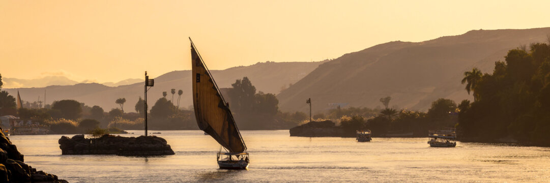 Felucca (traditinal egyptian sailing boat) on the Nile river at sunset in Aswan, Egypt panoramic travel web banner
