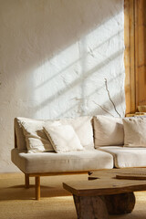 Bright cozy living room with light beige sofa, rustic wooden coffee table and sunlight streaming...