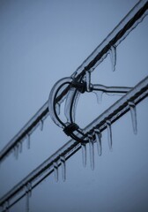 Obraz premium Ice-covered telephone wires with hanging icicles. Close-up of frozen power lines after a winter storm. Cold freezing weather background