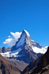 Fototapeta premium Snow Capped Mountain Peak Landmark in Daylight A majestic snow capped mountain peak under a clear, bright blue daylight sky. The surrounding landscape is rugged and natural, with hints of rocky