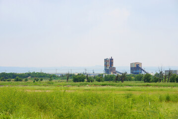 Abandoned rusted factories in a green field.