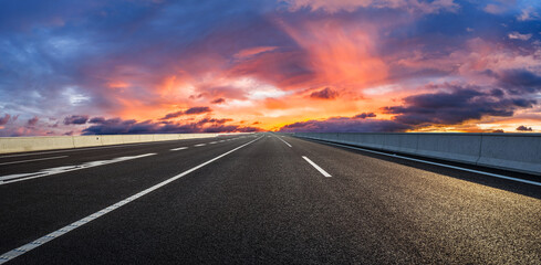 Asphalt highway road and colorful sky clouds at sunset