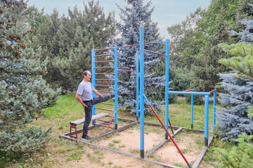 Active Senior Man Stretching on Outdoor Gymnastics Equipment in a Park