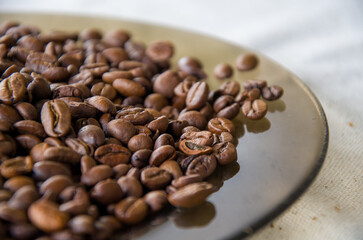 Macro Close-up of Rich Roasted Coffee Beans Piled on a Dark Reflective Plate