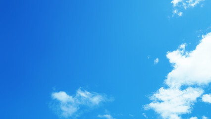 Clear blue sky with soft white clouds on a bright sunny day