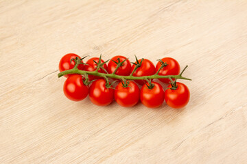 Red small tomatoes on a branch on a wooden background