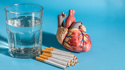 Symbolic representation of health choices with a heart model, glass of water, and cigarettes against a vibrant blue background