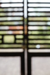 A blurred sleek black gate closes to a lush garden, basking in golden sunlight, inviting exploration.