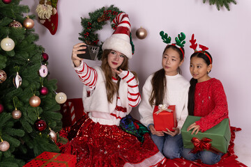 The girls are taking a Christmas selfie together while holding presents