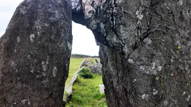 Cashtal yn Ard, Isle of Man, Neolithic stones framing a wide, open countryside view today.