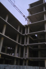 Unfinished building structure has no walls at dusk with crane.