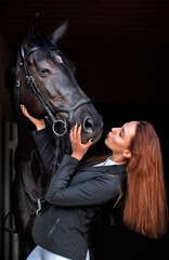 Woman near horse. Rider in a black uniform