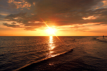 Golden Sunset over the Ocean. Stunning nature scene captures the essence of the golden hour as the bright sun dips low, illuminating the sky in vibrant shades of deep orange, yellow, and amber.