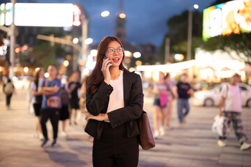Asian businesswoman talking on cell phone at night