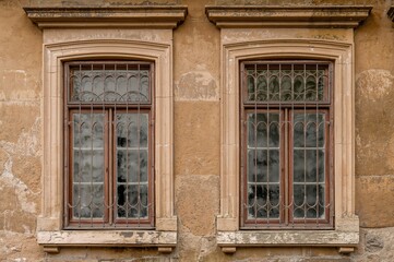 Fototapeta premium Old Windows Secured with Decorative Grilles on a Stone Facade