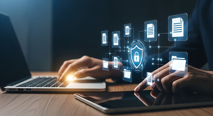 Person using laptop and tablet with data security shield and documents icons hovering above the devices.