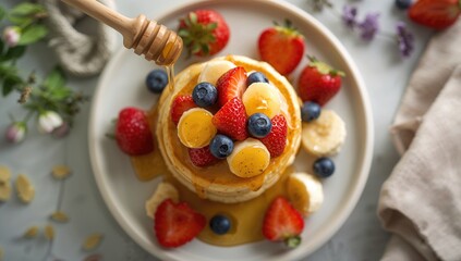 Obraz premium Small pancakes stacked with fresh fruit and topped with honey drizzle