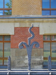 Grey ornamental metal fence finial in front of brick facade Dresden. Close-up. Copyspace