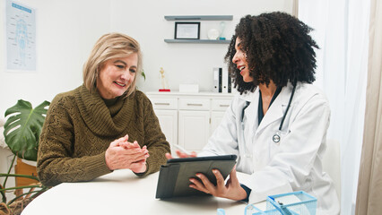 Fototapeta premium Medical Consultation With Doctor And Elderly Patient Sharing Tablet In Clinic Setting, Friendly Care