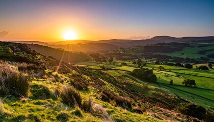 Fototapeta premium Golden hour paints a vast vista with rolling hills, meadows, and distant peaks. The radiant sun casts long shadows, highlighting textures