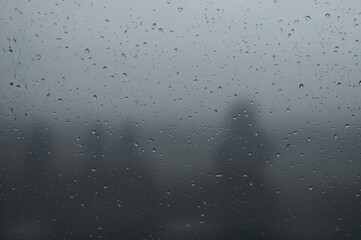 Obraz premium Raindrops on a foggy glass pane with a muted gray backdrop, evoking a rainy ambiance
