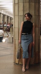 Beautiful brunette stands at the metro station waiting for the train to arrive