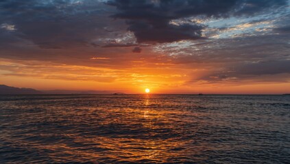 Obraz premium Evening sun casting vibrant orange hues over tranquil water reflections, serene seascape scene for relaxation and exploration.