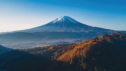 Fototapeta premium Aerial view of mountains with autumn foliage and a blue sky, showcasing seasonal change