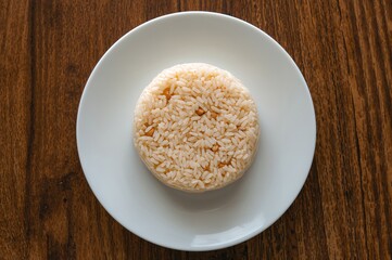 Overhead shot of a traditional sticky rice cake filled with beans on a white dish set on a wooden surface