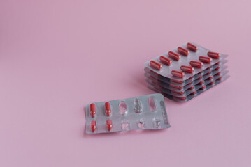 red tablets in blister packs are stacked on a pink background with space for text, allergy...