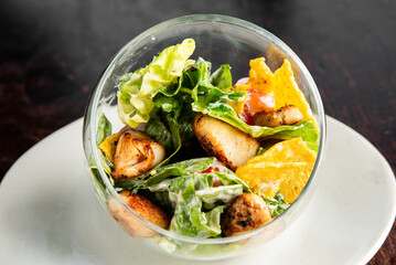 A close-up shot of a gourmet Caesar salad with chicken, romaine lettuce, croutons, and a creamy...