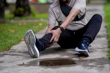 A young male runner clutching his knee in pain after an outdoor jog, highlighting sports injury and physical strain.