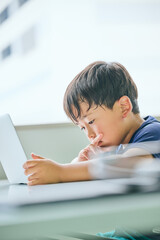 ノートパソコンでオンライン学習をする小学生の男の子