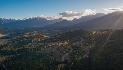 Aerial view of a mountainous rural landscape featuring a winding road, showcasing seasonal change