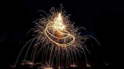 Long exposure of a burning sparkler creating spiraling light patterns against darkness