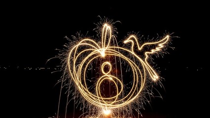 Illuminated, glowing sparks create a heart shape with an "8" and a bird silhouette against darkness