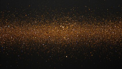 Fototapeta premium Shiny golden glitter scattered on a black surface, ideal for creative projects