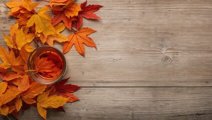 Flat lay arrangement featuring a cup of tea surrounded by autumn leaves on a wooden surface, suitable for editorial header background