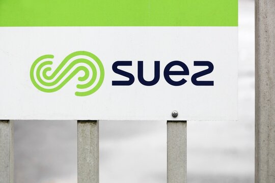 Regni&eacute;, France - September 22, 2024: Suez logo on a fence. Suez SA is a French-based utility company which operates largely in the water treatment and waste management sectors	