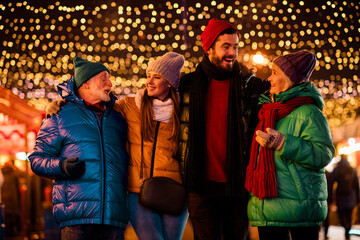Joyful family and friends celebrate together at a festive outdoor market under twinkling lights with warm coats and smiles during a merry Christmas night