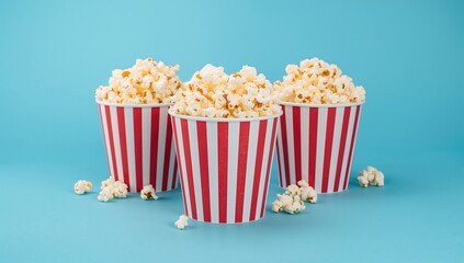Striped red and white containers filled with salted popcorn on a vibrant backdrop. Entertainment and cinema theme. Movie evening snack. Tasty treat with space for text
