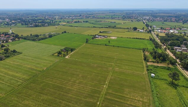 Aerial view of agricultural land featuring a grassy expanse and farmland, suitable for housing development - Powered by Adobe