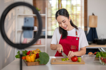 Woman cooking healthy food streaming online in kitchen