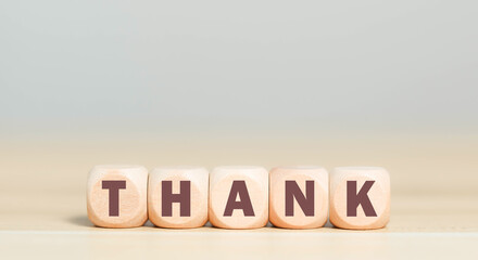Wooden blocks with the word THANK on a light background, symbolizing gratitude, appreciation, and positive communication for business or personal use in thank you cards or marketing design.