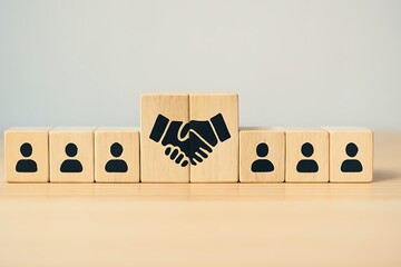 Business handshake symbol on wooden blocks with people icons representing teamwork and partnership