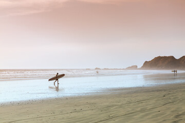 Surfer walking on the beach at sunset, Costa Rica