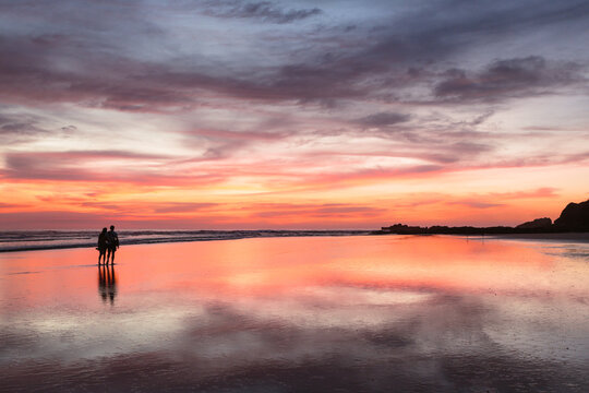 Couple at sunset walking on beach, Playa Guiones, Costa Rica
