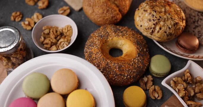 Closeup loop of macarons on plate with bagel and walnuts, dessert tabletop